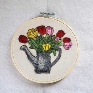 photo of needle felted tulips on cotton cloth background in embroidery hoop