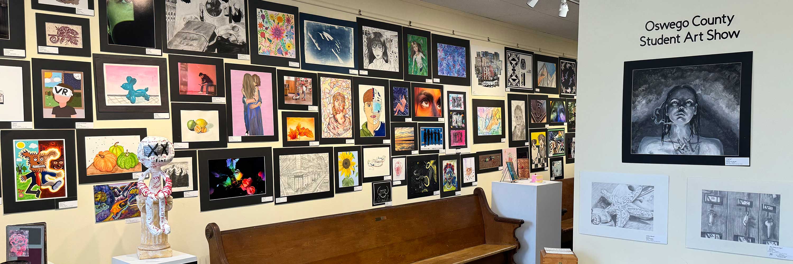 photo of wall of artwork from the Oswego County Student Art Show 2024