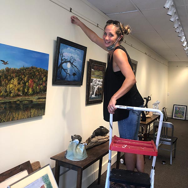 image of a volunteer hanging a painting for an upcoming show
