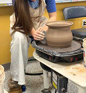 an image of a teenager working at a pottery wheel