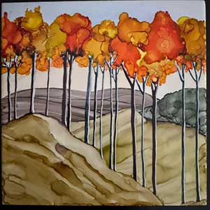 a ceramic tile painted with alcohol ink showing fall leaves on trees