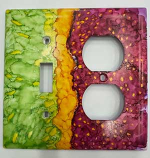 a photo of a ceramic light switch beautifully colored by alcohol ink