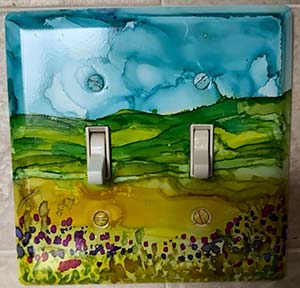 a light switch with a scene painted on it with alcohol ink