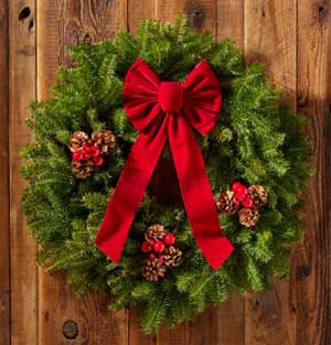 a photo of a green wreath with a red bow, pine cones and red berries