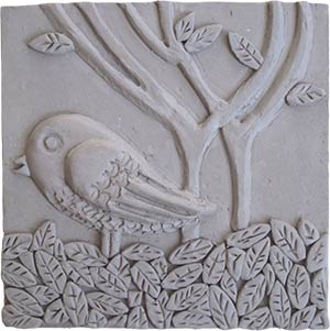 a 6-inch x 6-inch gray, unglazed and unpainted ceramic tile of a bird, leaves and trees