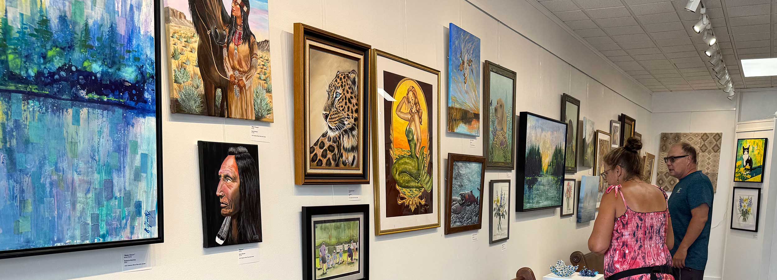 a photo showing two people looking at artwork from the 2026 Sunday Artist Show