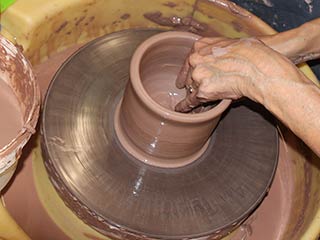 a photo of someone forming a pot on a pottery wheel