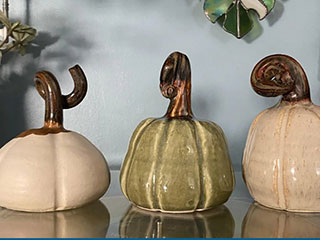 a photo showing three pottery pumpkins