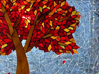 a glass mosaic of a tree in fall with red and gold leaves