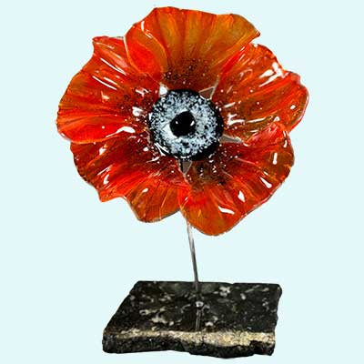 bright orange glass flower, with gold colored stem, standing on a black base